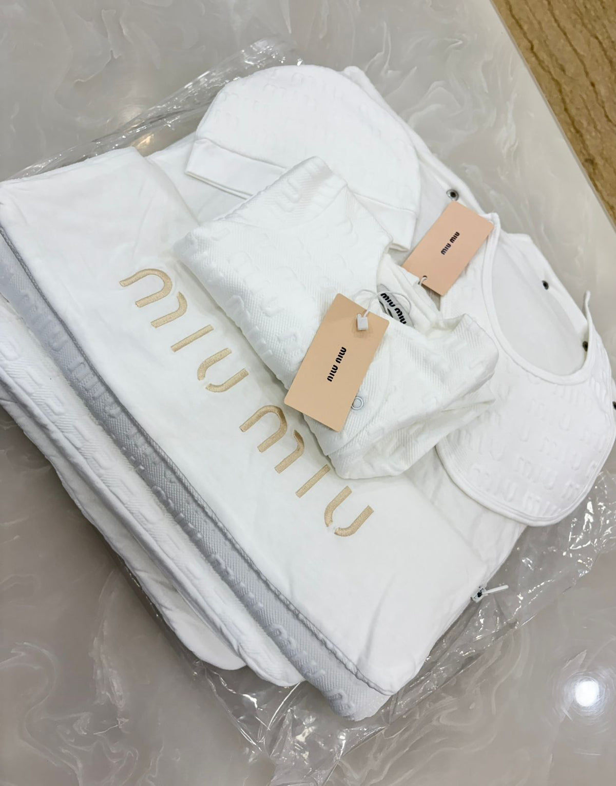 Miu Miu infant set features a branded embroidered blanket, bib, and cap